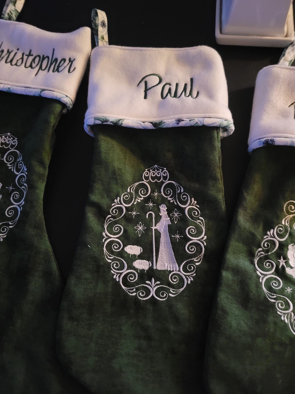 Personalized green velvet Christmas stockings embroidered with names and a nativity design