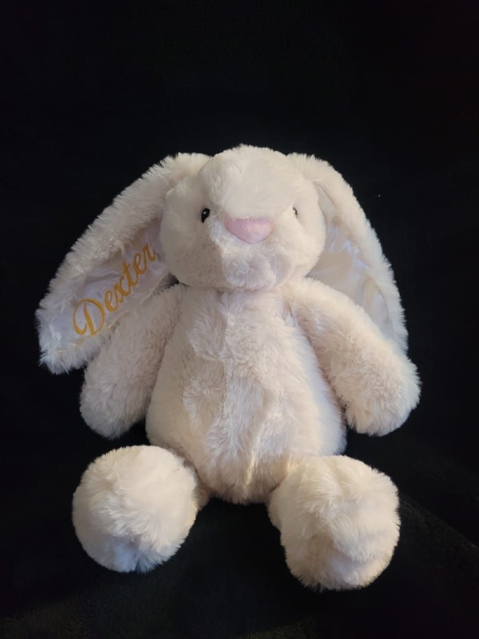 A plush cream bunny with the name Dexter embroidered in gold on its ear